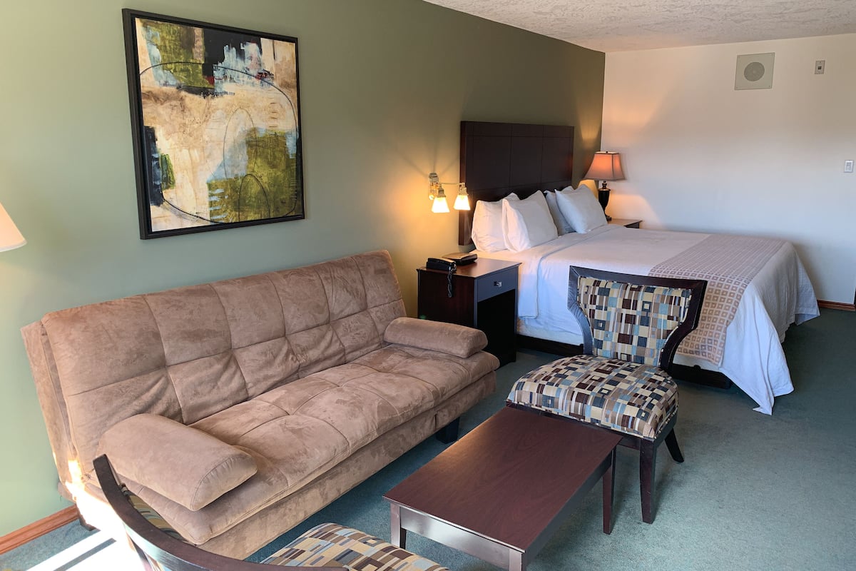 Een hotelkamer met een groot bed, een bank, een stoel en een tafeltje.