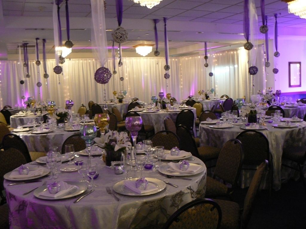 Un salón de banquetes con mesas redondas dispuestas para un evento formal, con manteles blancos y cubertería de plata.