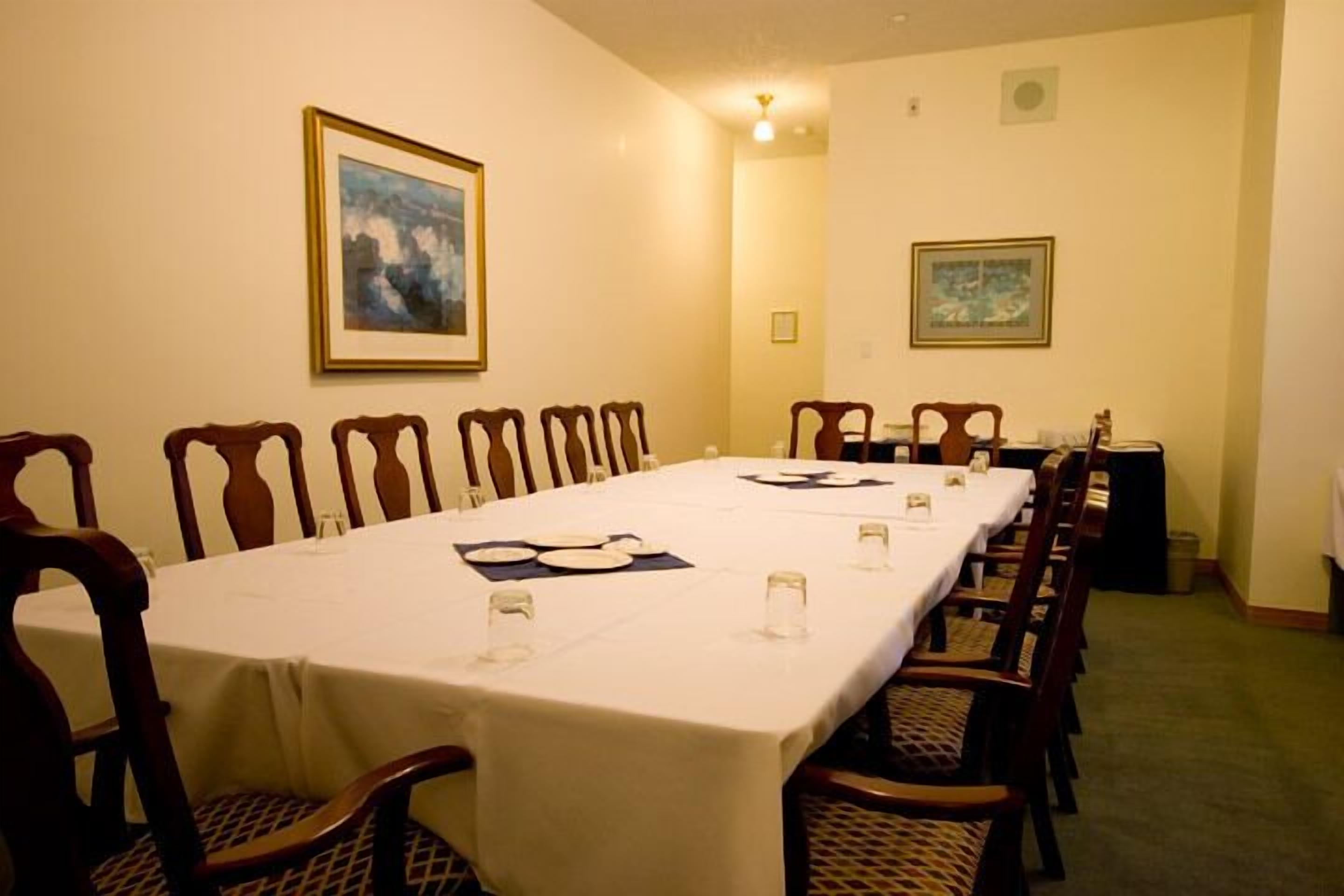 A conference room with a long table, chairs, and framed artwork on the walls.