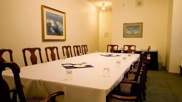 A conference room with a long table, chairs, and framed artwork on the walls.