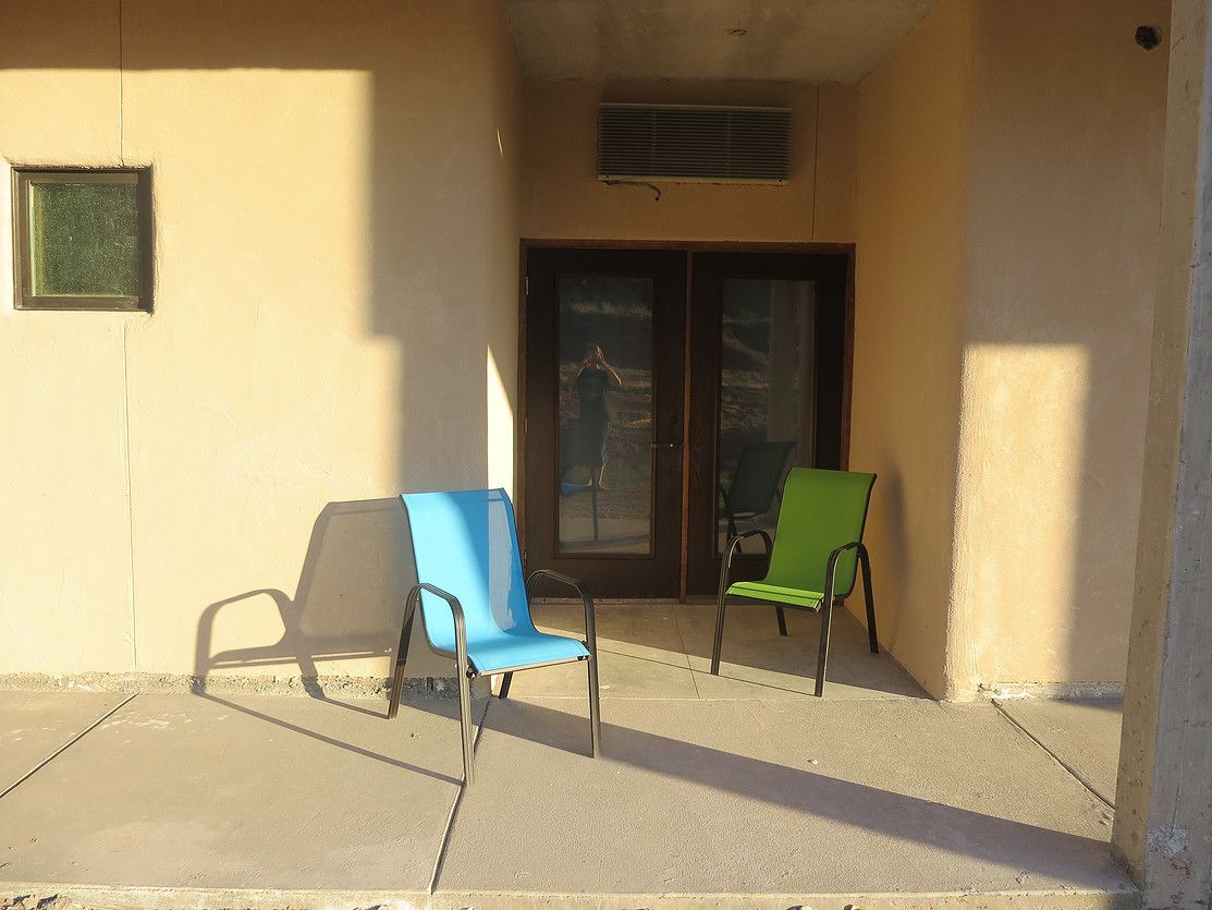 A building entrance with two chairs, a door, and a vent.