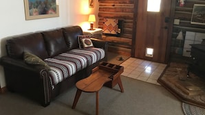 A cozy living room with a leather sofa, a wooden coffee table, and a fireplace. - La Posada Pintada (Bluff)
