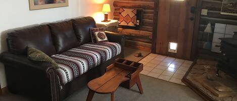Una sala de estar acogedora con un sofá de cuero, una mesa de centro de madera y una chimenea.