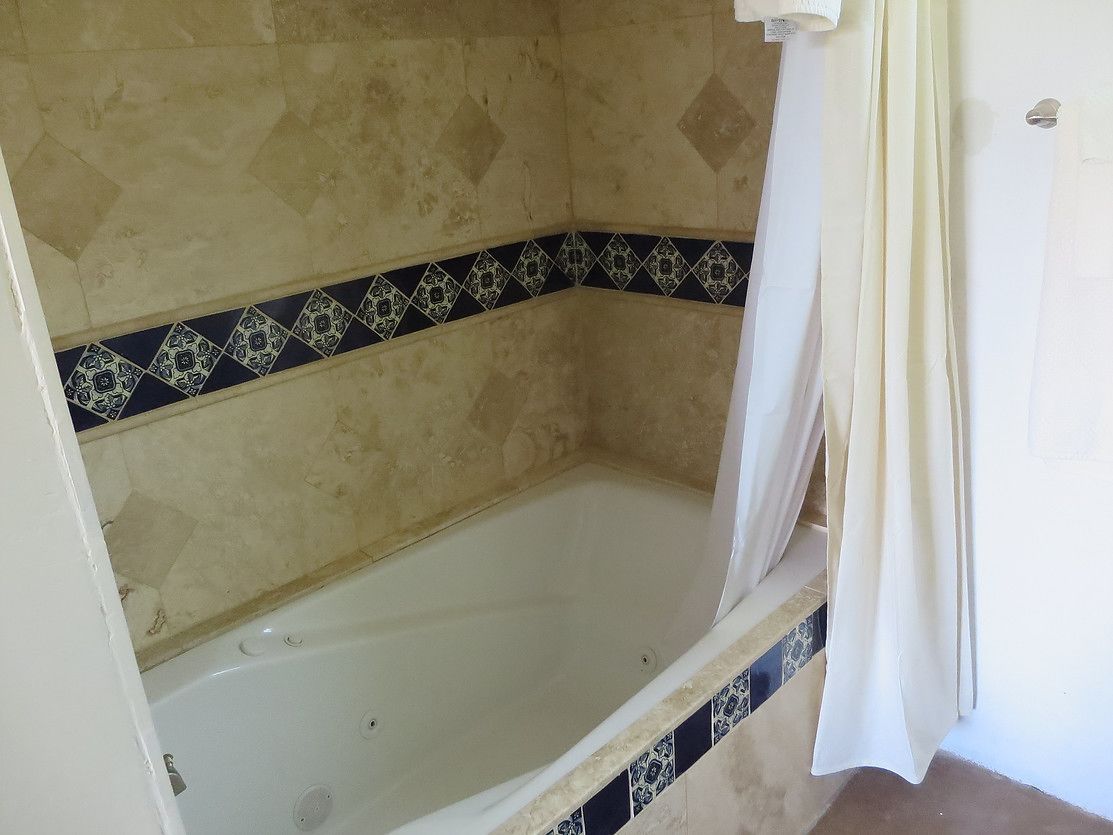 A bathroom with a bathtub, a shower curtain, and patterned tiles.