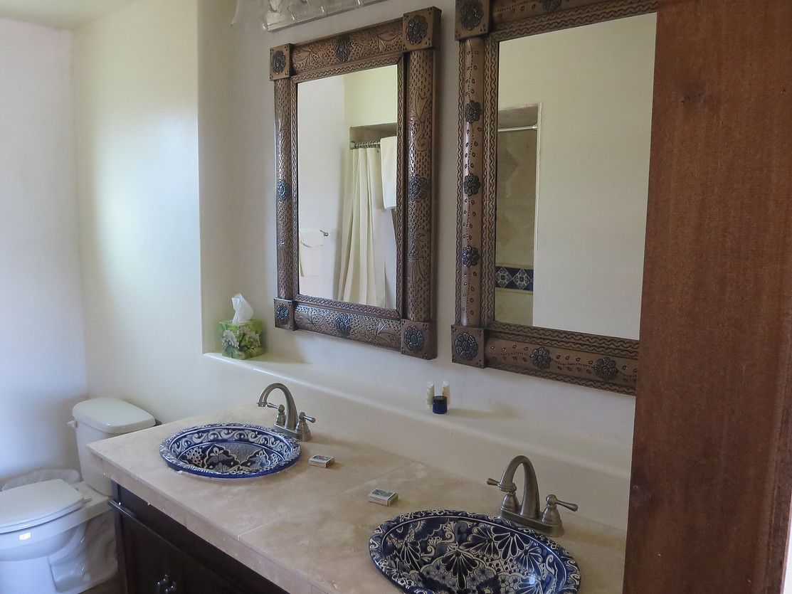A bathroom with two sinks, a toilet, and a large mirror with ornate frames.