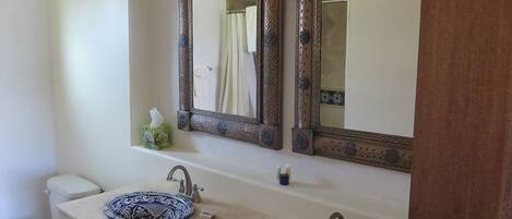 A bathroom with two sinks, a toilet, and a large mirror with ornate frames.