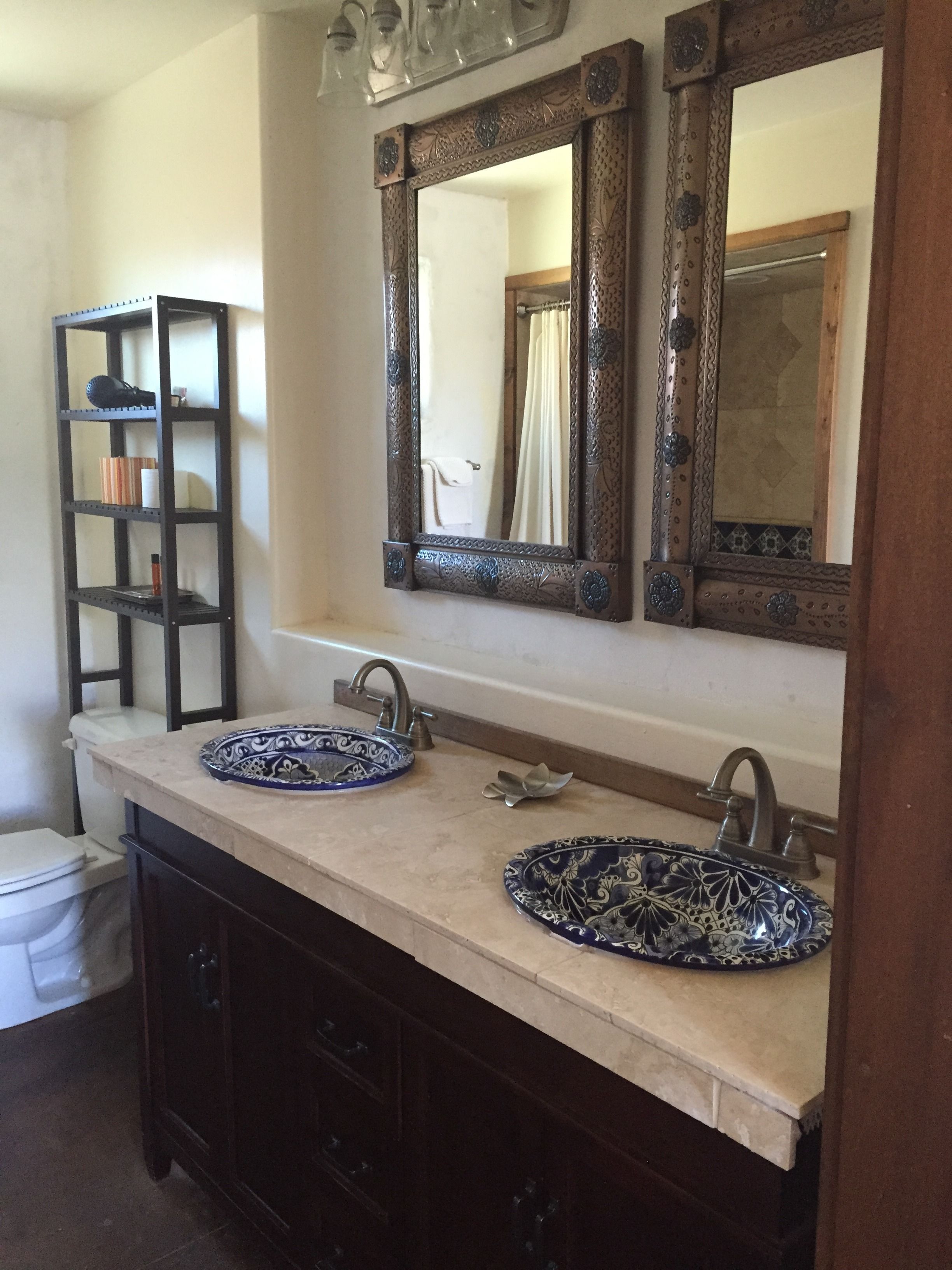 A bathroom with two sinks, a mirror, and a shelf with toiletries.