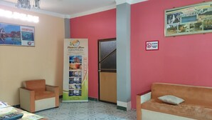 A reception area with a reception desk, two armchairs, a large vertical signboard, a no-smoking sign, and a framed picture on the wall.