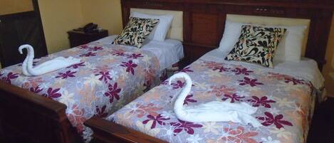 Una habitación de hotel con dos camas, cada una con ropa de cama floral y toallas decorativas con forma de cisne.