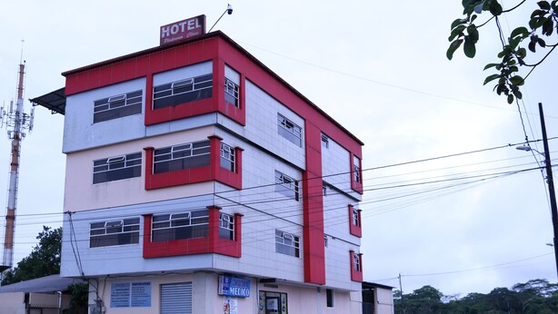 A multi-story building with a red and white facade, featuring a sign for a hotel and a medical clinic. - Platinum Class Hostal (Nueva Loja)