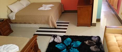 Ein Hotelzimmer mit einem Bett, einem Holzschrank, einem Streifen Teppich und einem blumigen, blauen Teppich.