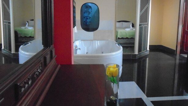 A bathroom with a large bathtub, a mirror, and a sink.