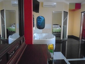 Un baño con una bañera grande, un espejo y un lavabo.