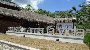A sign for 'ecuadora la vida' with a thatched roof structure and a logo for 'Parque Turístico Nueño Loja'.