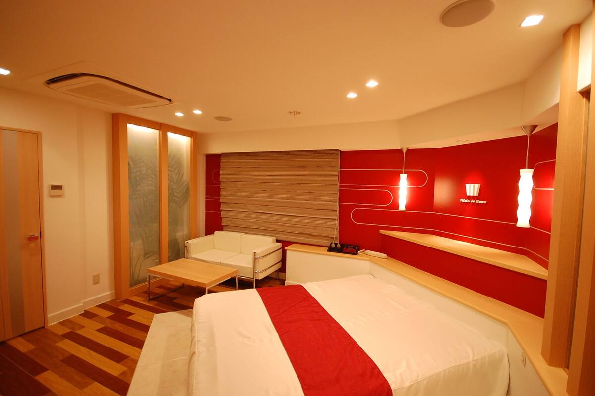 Une chambre d’hôtel avec un lit, un bureau, une chaise et un mur d’accent de couleur rouge.