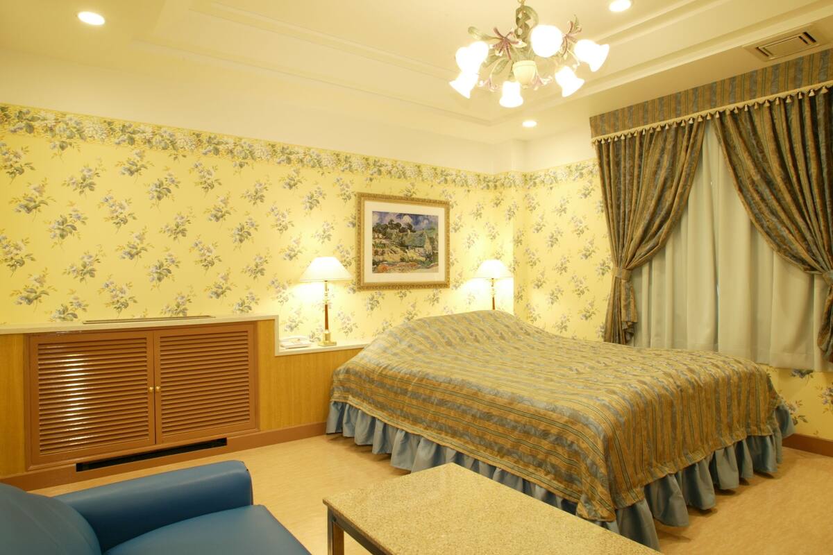Une chambre à coucher comprenant un lit, un bureau, une chaise, une armoire et un tableau accroché au mur.