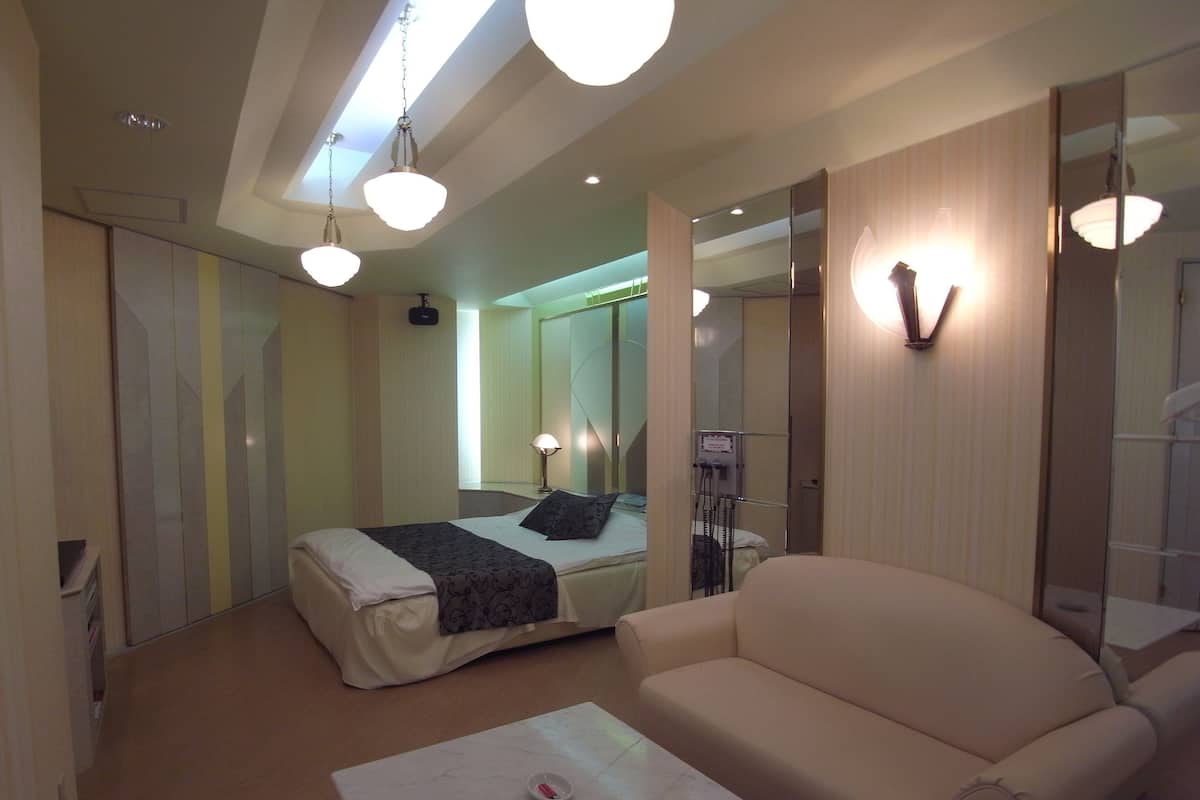 Une chambre d’hôtel avec un lit, un canapé, une petite table et un miroir.