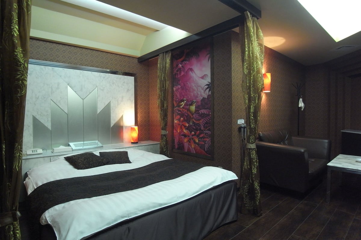 Une chambre d’hôtel avec un grand lit, un bureau, une chaise, un miroir et un tableau au mur.