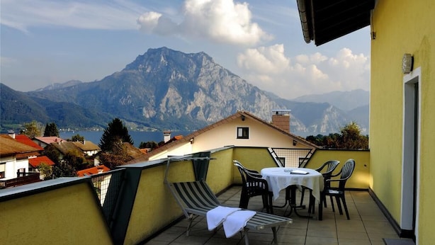 A balcony with a table and chairs, overlooking a mountain range. - Pension Bruderhofer (ALTMUENSTER)