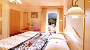 A hotel room with a bed, a desk, a chair, and a view of mountains through a window. - Pension Bruderhofer (ALTMUENSTER)