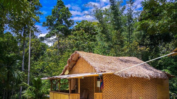 A thatched-roof hut with a wooden porch and steps leading to the entrance.