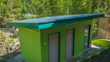 En liten, envåningsbyggnad med en grön fasad och ett blått tak, med två dörrar och ett litet fönster.