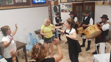 Un grupo de personas en una habitación con mesas y sillas, algunas tocando la batería.