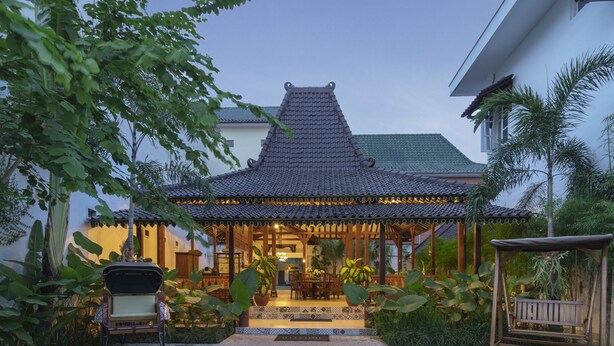A traditional-style building with a tiled roof, a covered porch, and a seating area with a swing.