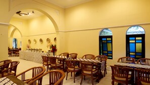 A dining area with wooden chairs and tables, a buffet setup, and decorative wall plates. - Hotel Diana Jogja (Yogyakarta)