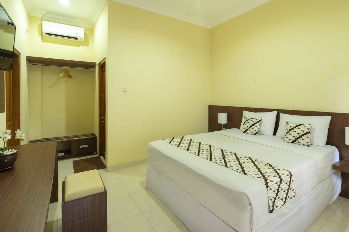 Una habitación de hotel con cama, mesita de noche y espejo.