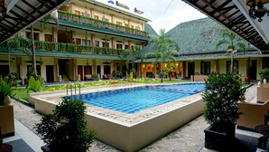 A courtyard with a swimming pool, outdoor seating, and a multi-story building with balconies.