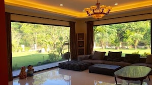 A spacious living room with a large window, a sofa set, a glass coffee table, and a chandelier. - Tainan California Villa (Tainan)