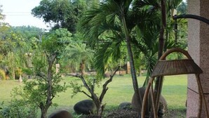 A garden with a tiled pathway, a wicker chair, and various plants and trees. - Tainan California Villa (Tainan)