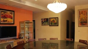 A conference room with a round glass table, surrounded by chairs, and a television on a stand. - Tainan California Villa (Tainan)