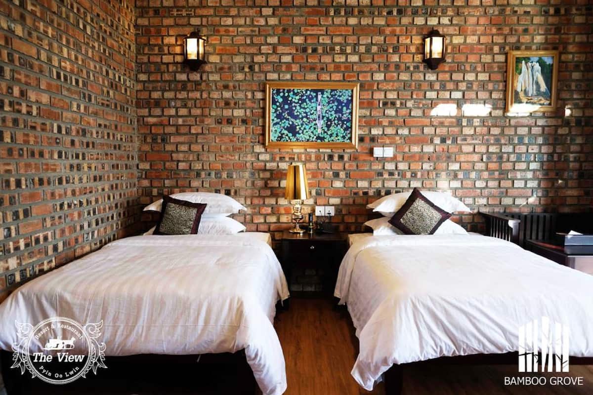 A room with two beds, a brick wall, a painting, and a framed picture.