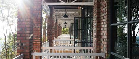 A covered outdoor area with a wooden bench, white railings, and brick walls.