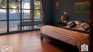 Une chambre avec une grande fenêtre, un lit, une table de chevet et une vue sur l’extérieur.