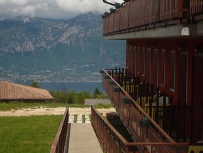 Un edificio rojo con un balcón que da a un paisaje montañoso y una masa de agua.