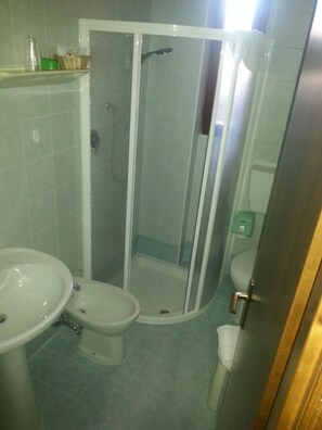 Un baño con cabina de ducha, lavabo e inodoro.