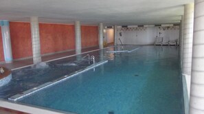 Una piscina interior con agua cristalina, paredes de azulejos y unos pocos escalones para entrar.