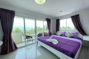 A hotel room with a large bed, a balcony with a view, and a seating area. - Bird Hotel (Chonburi)