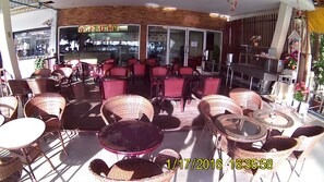 An outdoor seating area with wicker furniture and a glass enclosure. - Bird Hotel (Chonburi)
