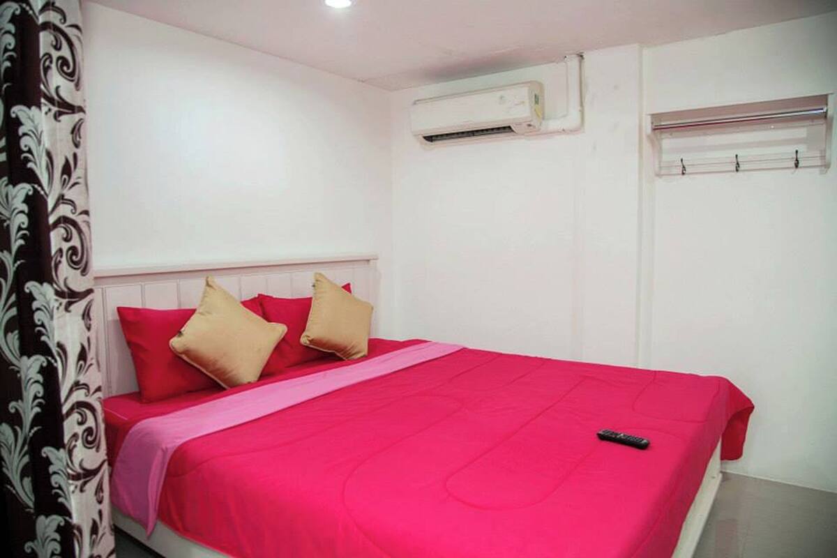 A room with a bed, air conditioning unit, and a window with curtains.