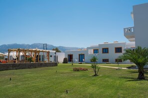 A modern building with a covered outdoor seating area and a well-maintained lawn. - Bouradanis (Kos)