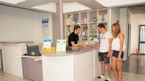 Una mesa de recepción con una computadora portátil, un letrero de recepción y una estantería con varios objetos.