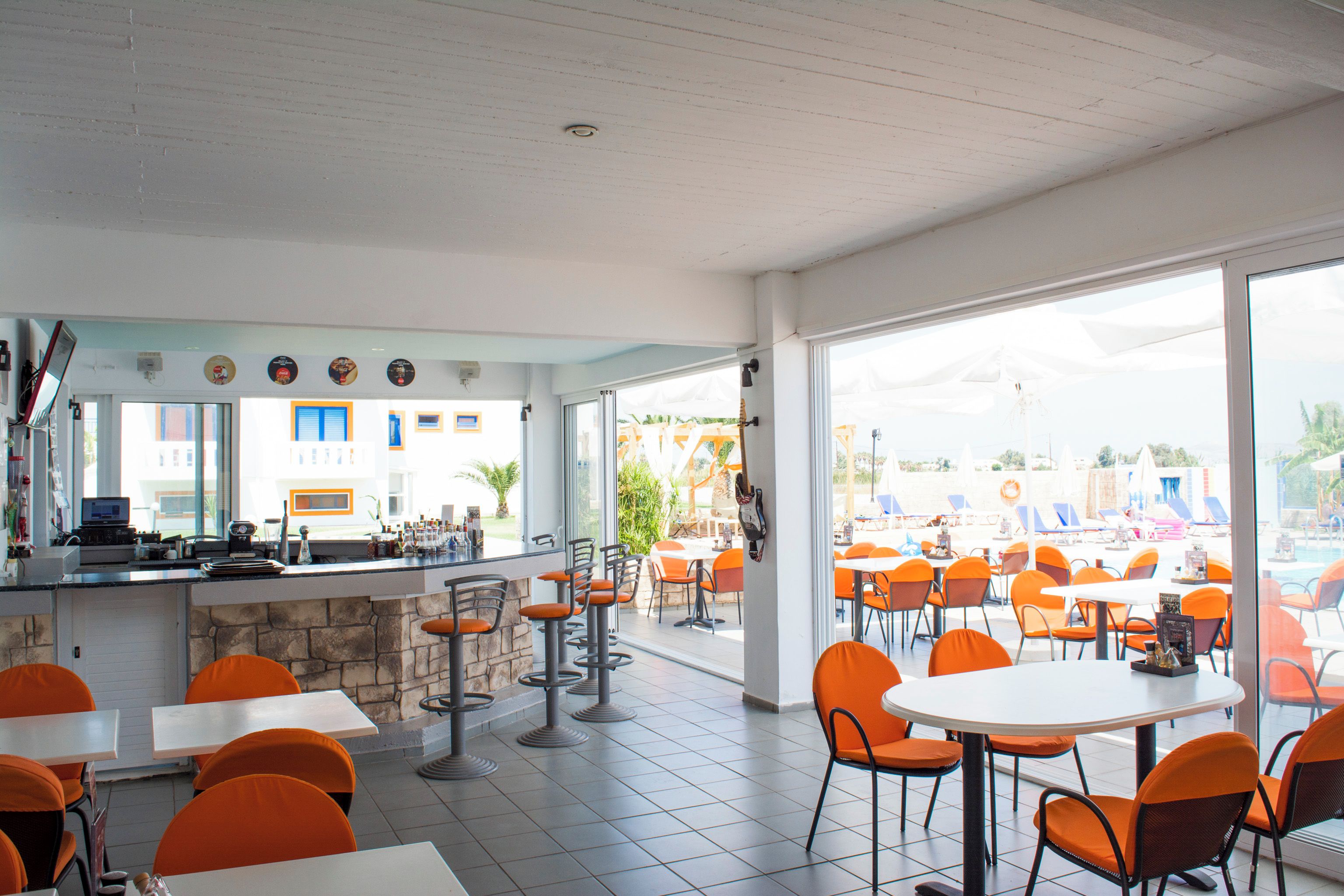 En restaurang med en bardel, uteservering och stora fönster.