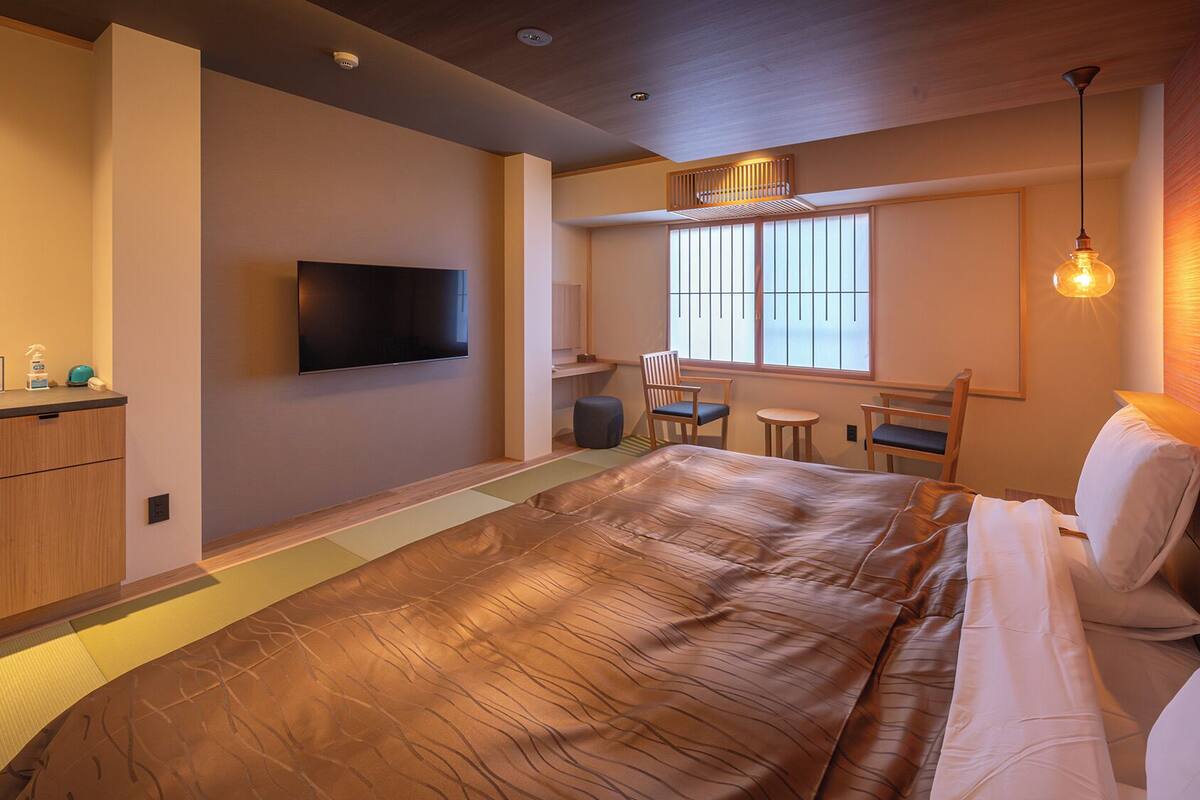 A hotel room with a bed, a TV, a desk, and a chair.