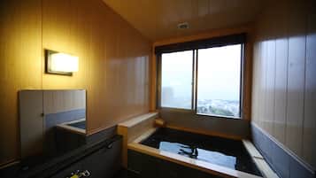 Une salle de bain avec des lambris en bois, une baignoire, un lavabo et une fenêtre donnant sur la ville.