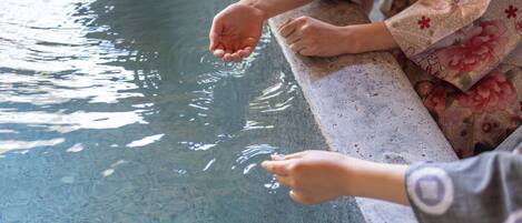 A person in traditional attire by a pool with clear water.