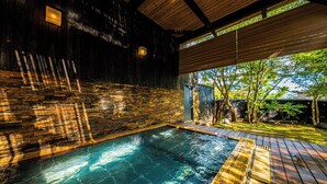A hot tub area with a wooden deck and stone walls.